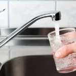 Man filling glass of water from kitchen sink