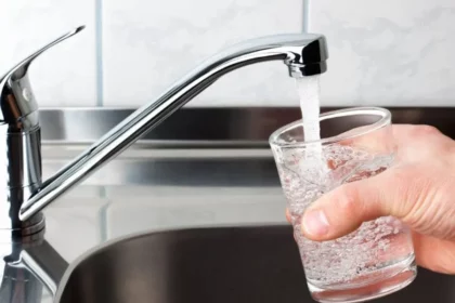 Man filling glass of water from kitchen sink