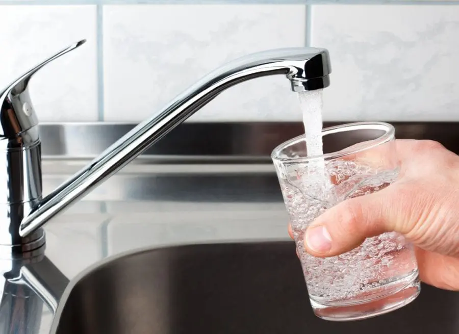 Man filling glass of water from kitchen sink