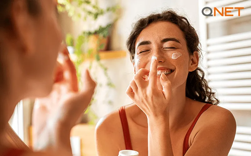 happy woman putting sunblock on her nose