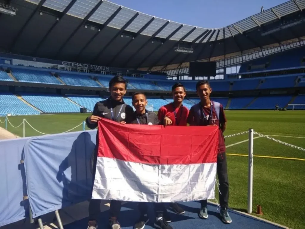 QNET Indonesia manchester city kids posing on stadium field