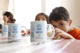 School children with cups advocating water conservation through 'Save Water' messages.