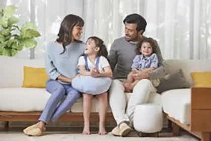 A family of four happily gathered on the living room couch, with a nearby HomePure ensuring clean and purified air.