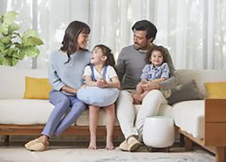 A family of four happily gathered on the living room couch, with a nearby HomePure ensuring clean and purified air.