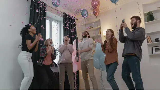 Group of friends celebrating a win in room with balloons everywhere