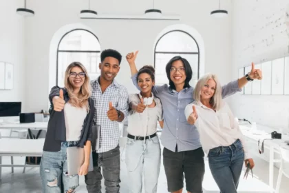 Group of young men and women in office giving thumbs up