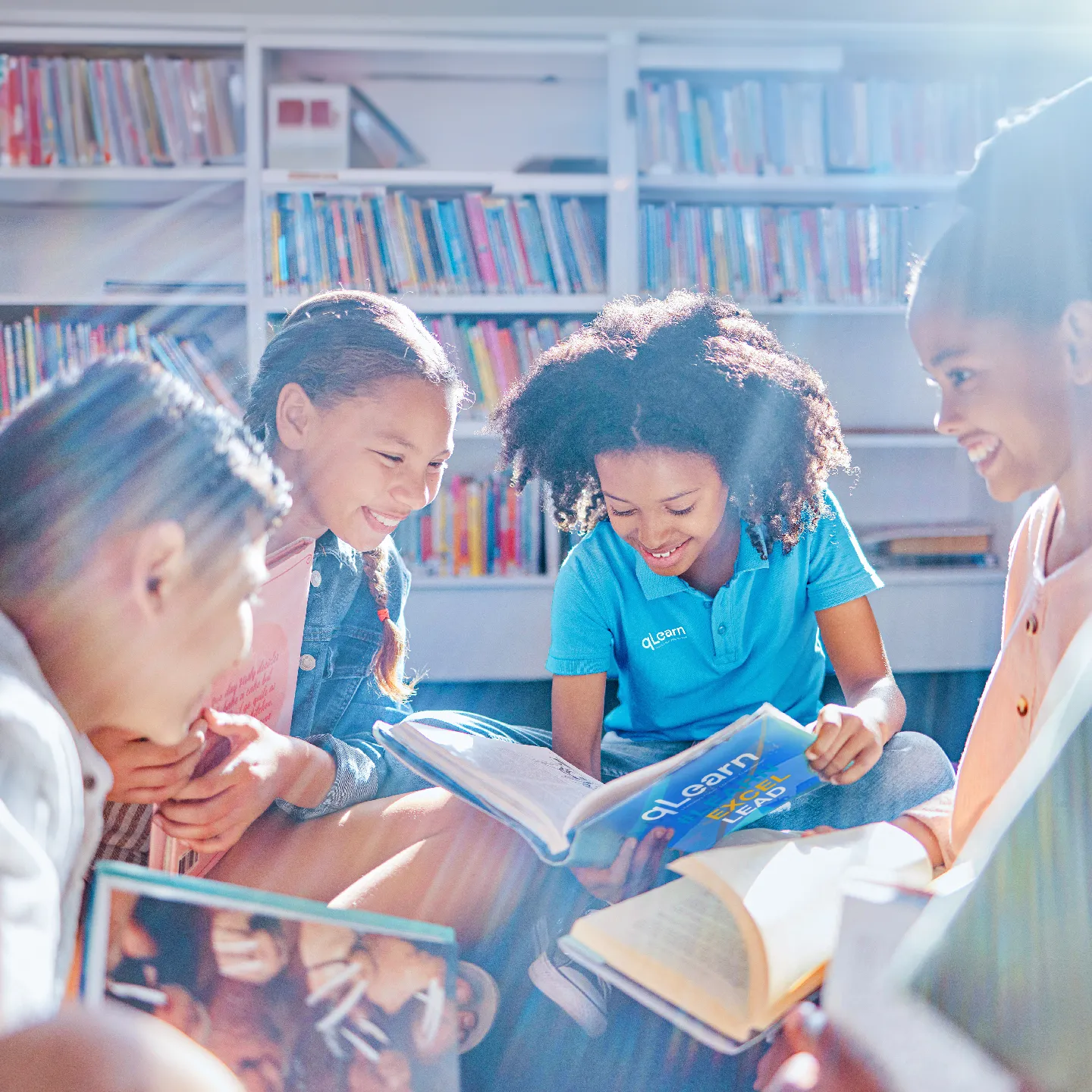 Kids huddled together as they read books for their qLearn course