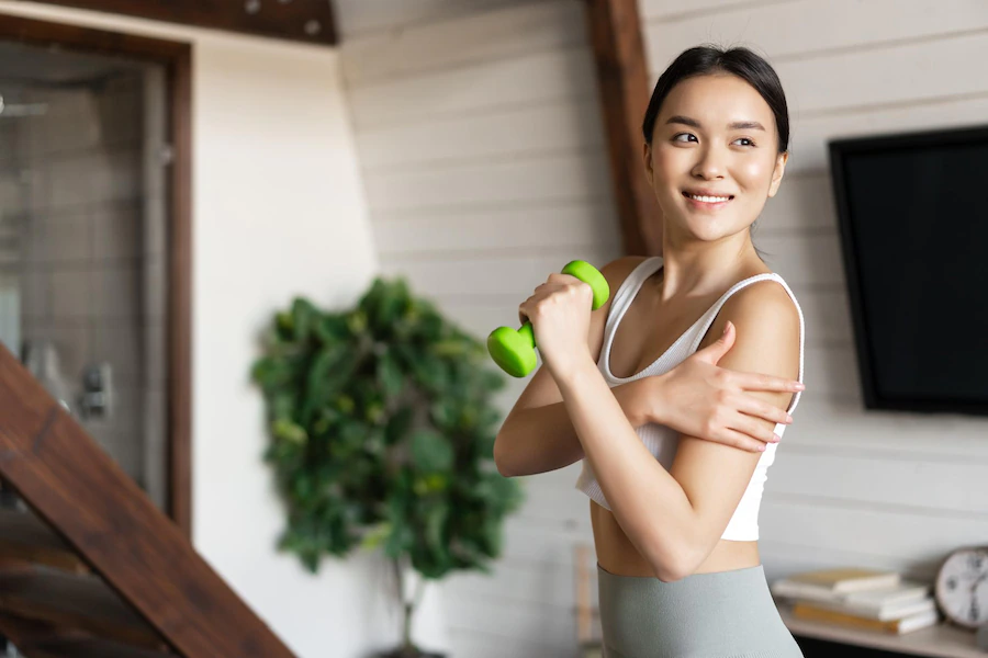 Woman exercising with a small dumbbell, reaping the benefits of a plant-based diet as part of her new year's fitness resolutions