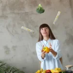 Woman who enjoys a plant-based diet juggling EDG3 Plus packets with broccoli and bell pepper