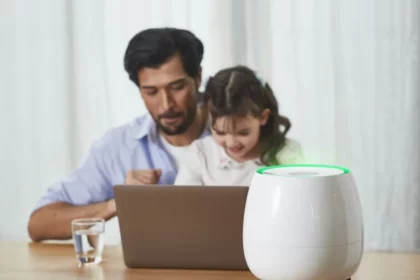 A father and his daughter sit at a table with a laptop, while HomePure Zayn ensures safe and clean indoor air