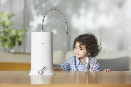 A young boy beside a kitchen counter, with a glass of water nearby, and a HomePure product on the table.