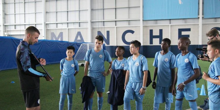 Kids learning football on City's Etihad campus in blue football uniforms