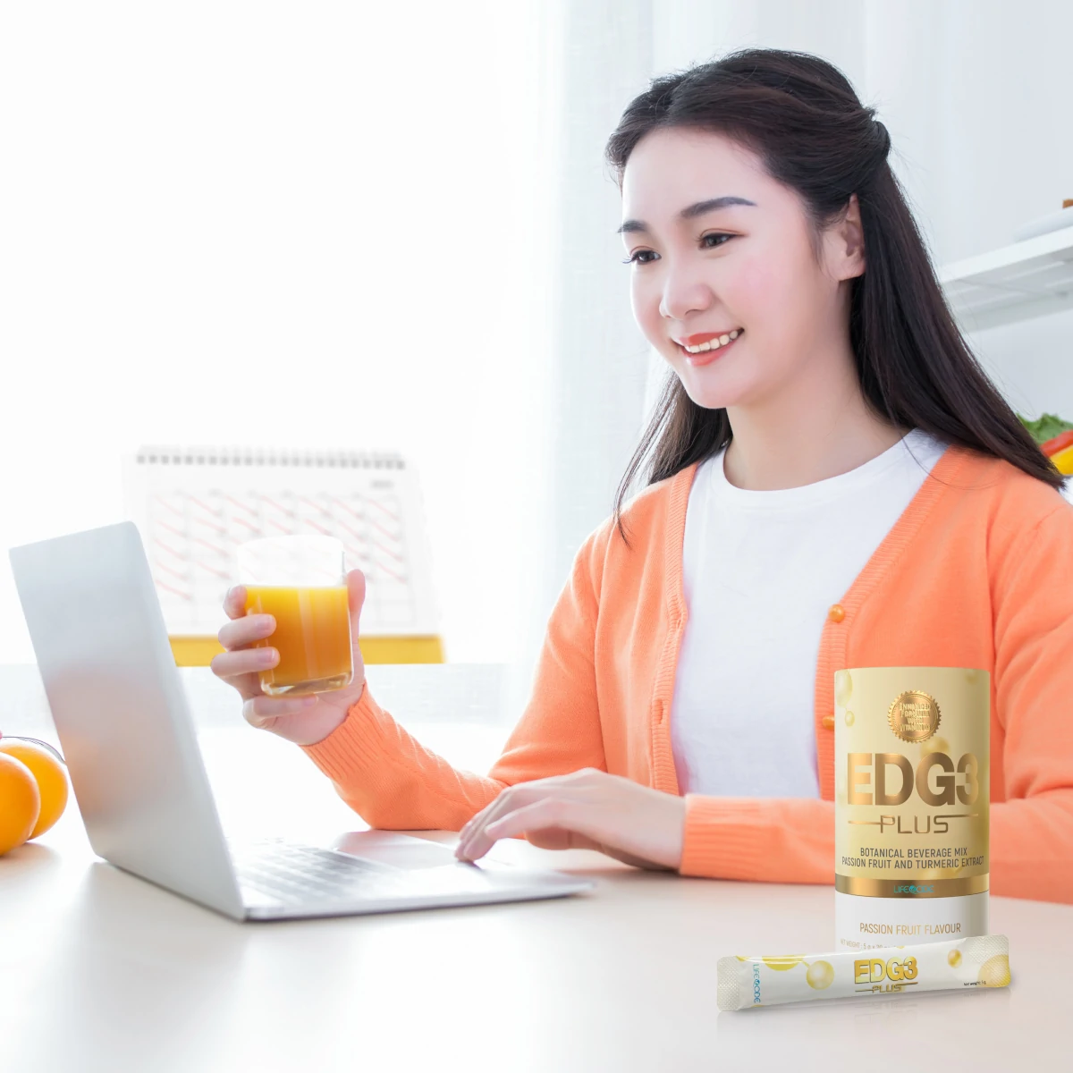 Middle aged woman drinking a cup of edg3 plus working on computer 