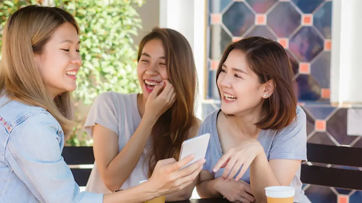 Three woman laughing together looking at phone