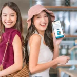 2 women smiling showing qbuzz on their mobile phones