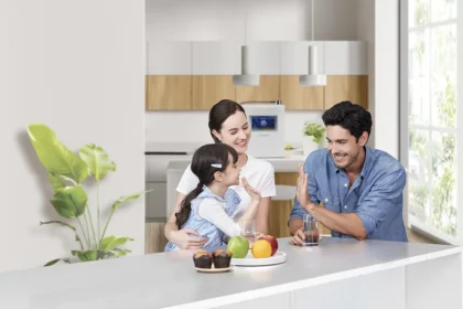 Young couple with a child at the kitchen with muffins, fruit, drinks prepared with the help of HomePure Viva water