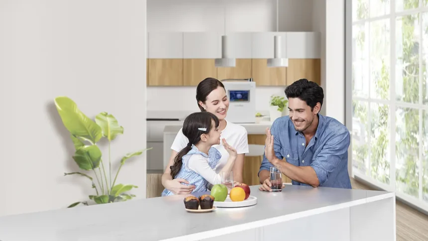 Young couple with a child at the kitchen with muffins, fruit, drinks prepared with the help of HomePure Viva water