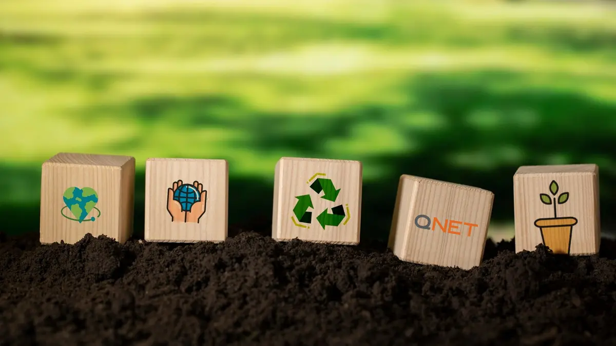 QNET Green Legacy sustainability icons on wooden blocks planted in the soil 
