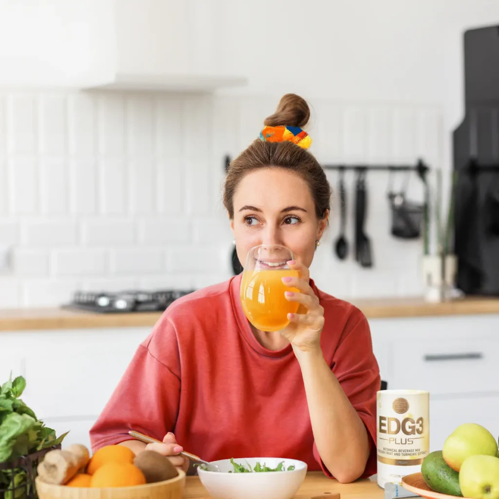 A woman is drinking a glass of EDG3 Plus while having a salad