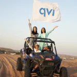 Girls on a jeep with a QVI flag, riding in the desert where they enjoyed stress-free travel to for their holiday