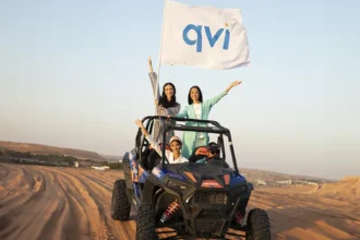 Girls on a jeep with a QVI flag, riding in the desert where they enjoyed stress-free travel to for their holiday