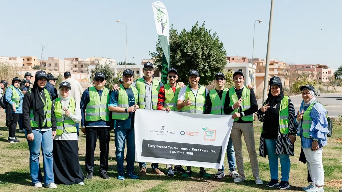 Smiling representatives pose with a banner bearing QNET, Bernhard H Mayer and Green Legacy branding to commemorate having planted a tree for every OMNI watch sold on 7 March 2024 in Cairo, Egypt.  