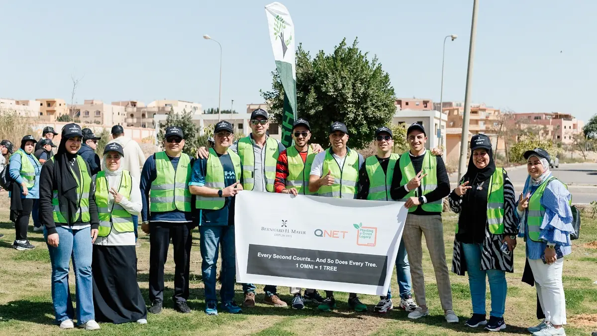 Championing Sustainability And Building A Green Legacy With Qnet 11 Smiling representatives pose with a banner bearing QNET, Bernhard H Mayer and Green Legacy branding to commemorate having planted a tree for every OMNI watch sold on 7 March 2024 in Cairo, Egypt.
