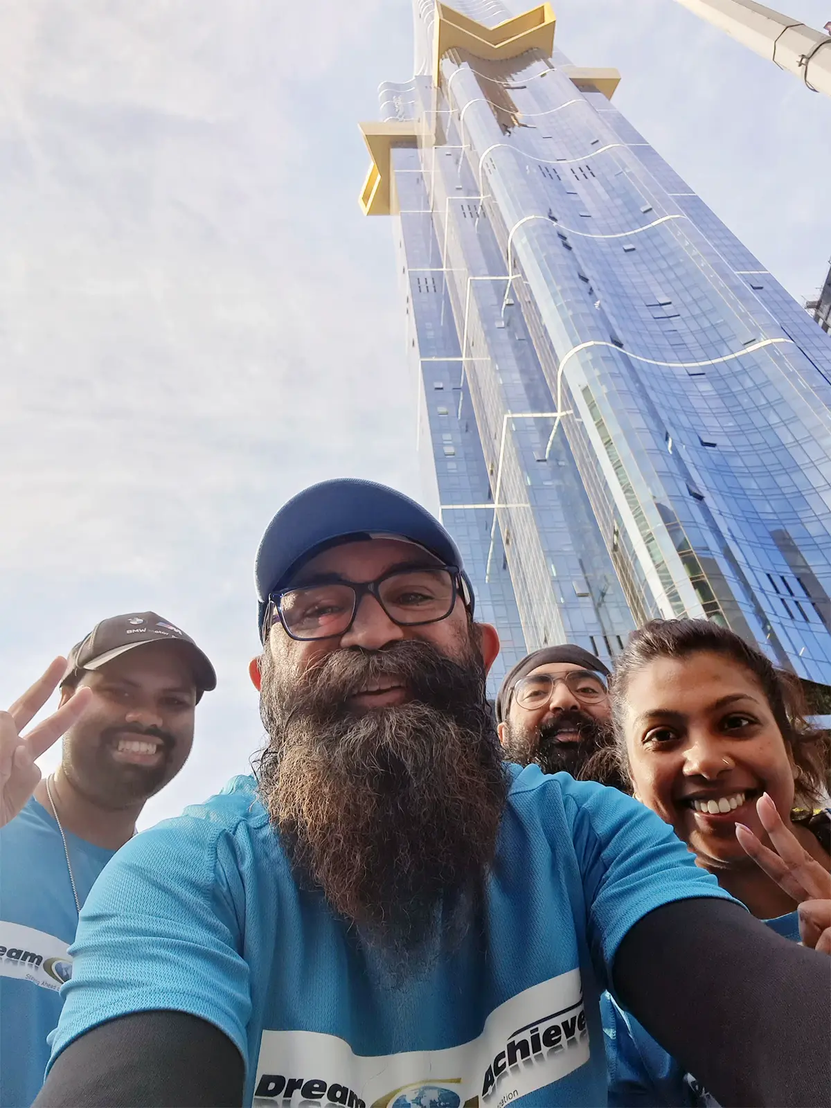Journey To The Top: Avp Perminderjit Singh Scales New Heights At 2024 Australia 108 Stair Challenge 2 AVP Perminderjit Singh with three members of DreamAchiever Team posing for a selfie in front of the Australia 108 tower