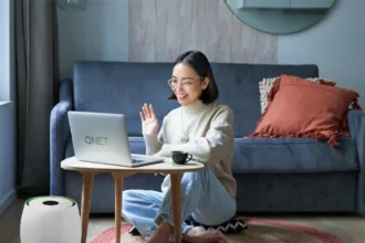 Girl who is doing QNET Part-Time talks to a business prospect on her laptop; she is wearing an Amezcua Chi Pendant and her home is equipped with HomePure Zayn