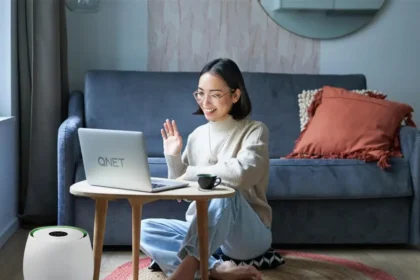 Girl who is doing QNET Part-Time talks to a business prospect on her laptop; she is wearing an Amezcua Chi Pendant and her home is equipped with HomePure Zayn